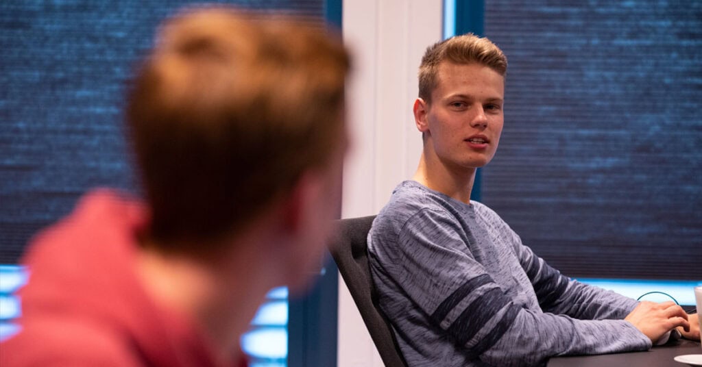 Twee mannen in overleg zitten achter het bureau.