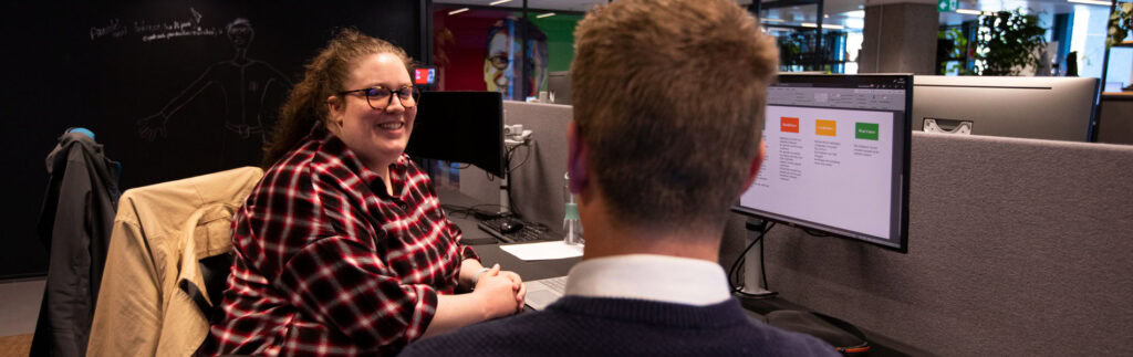 Vrouw en man in overleg aan tafel achter de computer op kantoor.