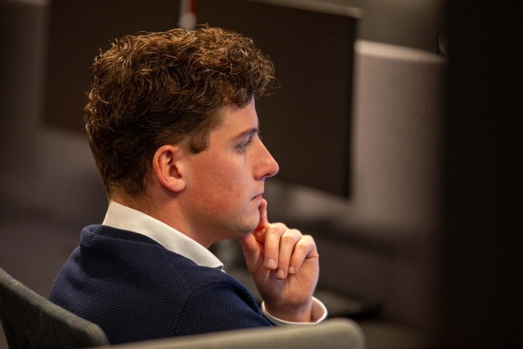 Foto van man op kantoor. Kijkt serious en is aan het werk