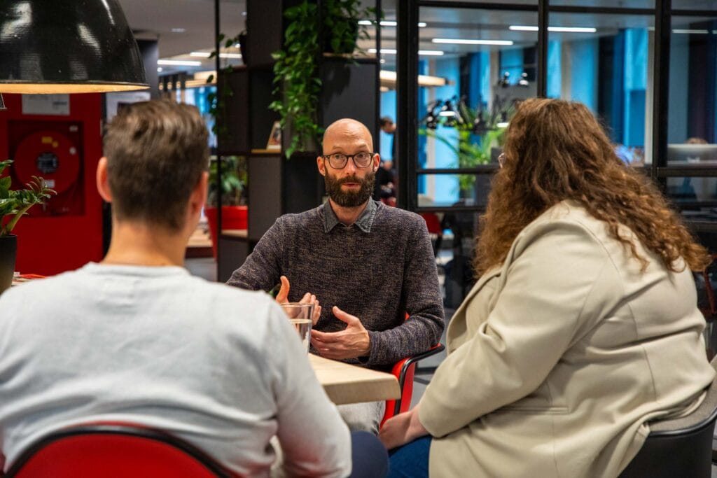 Foto van drie collega's in gesprek op het kantoor.