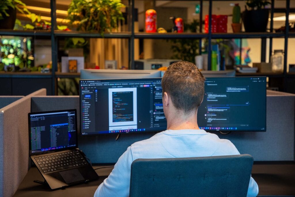 Collega is in het kantoor aan het werk achter beeldschermen.