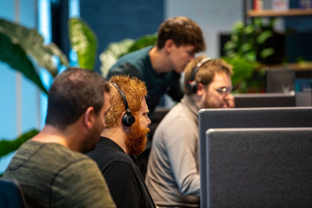 Collega's zijn aan het werk op kantoor. Ze zitten achter een bureau.